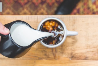 Pouring a healthy coffee creamer alternative into coffee