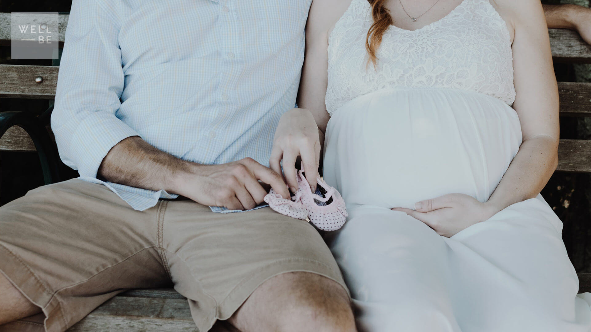 Pregnant couple holding baby shoes